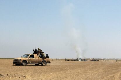 Rebeldes del grupo sirio islamista Jabhat Fateh al-Sham saludan desde una camioneta, cerca de los restos del helicóptero ruso derribado en la provincia de Idlib.