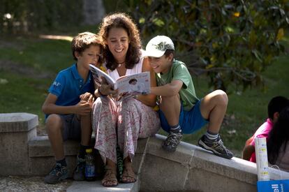 Una mujer mura un libro junto a unos niños durante la Feria del Libro de Madrid, el 30 de mayo de 2015.