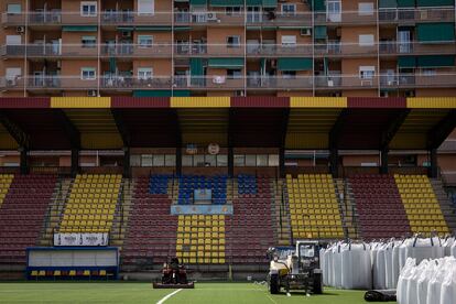 El estadio del Sant Andreu, en obras por el cambio de césped, con los bloques del barrio detrás.