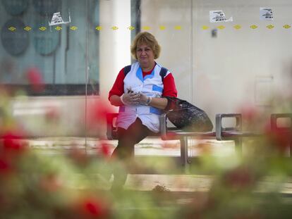 Una trabajadora espera el autobús en Sevilla, durante la limitación total de movimientos salvo para las actividades esenciales.
