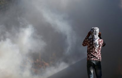 Un manifestante palestino observa cómo el humo aumenta durante los enfrentamientos con las fuerzas de seguridad israelíes tras una manifestación contra la expropiación de tierras palestinas por parte de Israel en la aldea de Kfar Qaddum, cerca de Naplusa (Cisjordania).