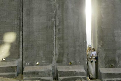 Una mujer palestina, con su hijo en brazos, pasa cerca de Jerusalén por un hueco en el muro levantado por Israel.