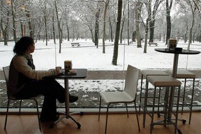 Una joven toma café en un bar mientras contempla el parque del Prado de Vitoria, cubierto por la nieve.