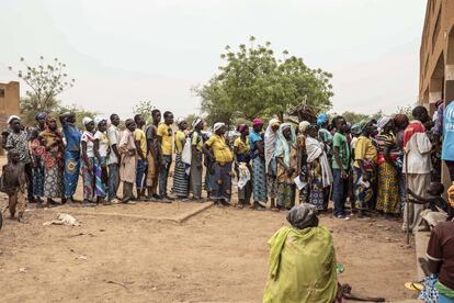 Decenas de desplazados por el conflicto en el norte de Burkina Faso hacen cola para el reparto de harina enriquecida llevado a cabo por la ONG Help en el Instituto de Educación Secundaria de Barsalogho.