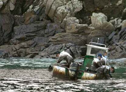 Marineros gallegos recogen fuel del <i>Prestige</i> en su barca junto a las islas Cíes.