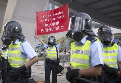 Un agente de policía, con un cartel en el que advierte de que las fuerzas de seguridad usarán la fuerza.