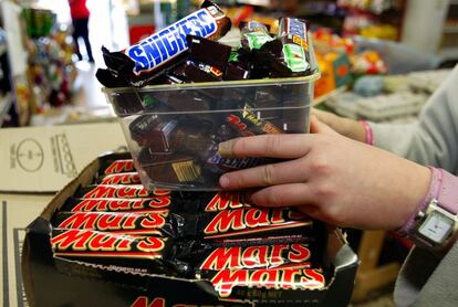 Un empleado coloca barritas Mars y Snickers en una estantería