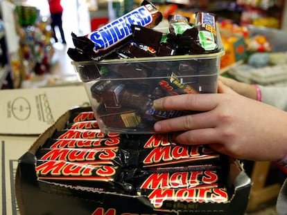 Un empleado coloca barritas Mars y Snickers en una estanter&iacute;a