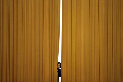 Un miembro del personal del Parlamento chino se asoma tras una cortina en el Gran Salón del Pueblo de Pekín (China).