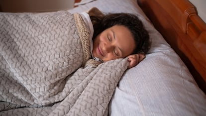 Una mujer tapada con una colcha de borreguito.