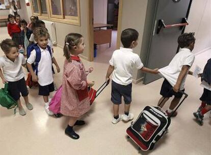 Varios niños con sus mochilas entran en clase.