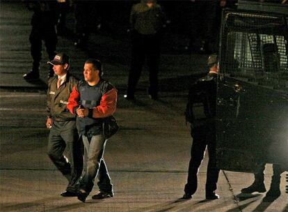 Un polica colombiano escolta a uno de los jefes paramilitares extraditados en la madrugada de ayer a Estados Unidos.