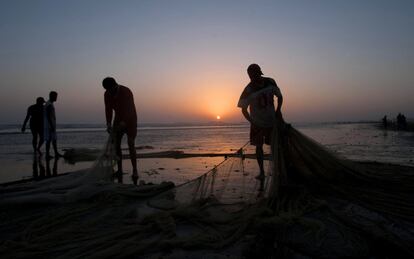 Pescadores pakistaníes preparan sus redes al atardecer en la costa del Mar Arábigo, en Karachi (Pakistán).