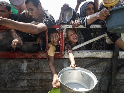 Palestinos con sartenes se reúnen para recibir comida caliente distribuida por una organización benéfica en la ciudad de Gaza, el 23 de julio de 2025