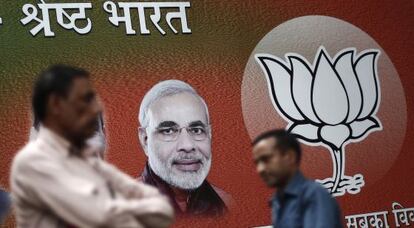 Varios hombres pasean frente a un cartel del candidato hindú, Narendra Modi.
