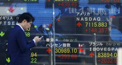 Un peatón camina frente a una pantalla que muestra indicadores financieros este miércoles 7 de febrero de 2018, en Tokio (Japón).
