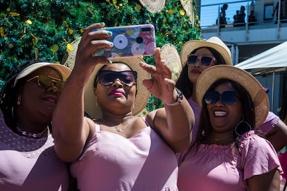 Cuatro amigas de visita en Ciudad del Cabo se toman una foto junto al árbol de navidad instalado en la zona comercial Victoria & Alfred Waterfront, en Ciudad del Cabo. Tanto ellas como otras ocho que no salen en la imagen provienen de los alrededores de la provincia y han decidido juntarse después de meses de separación a causa de la pandemia de covid-19. Todas visten igual, con vestidos rosas y sombreros de paja. Pincha en la imagen para ver la fotogalería completa.