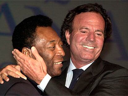El cantante Julio Iglesias saluda afectuosamente al <b></b><i>cantante</i> Pelé, ambos embajadores de Unicef, durante el acto celebrado ayer en Sevilla con motivo de la reunión anual del Fondo Mastercard de Ayuda a la Infancia.