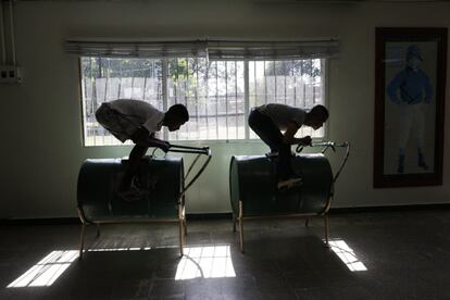 Dos jóvenes practican para ser jinetes de carreras en unas estructuras que simulan caballos construídas con antiguos bidones de petróleo y a la que denominan 'Pangal'. La fotografía se tomó en la Escula de Jockeys de Panamá el 11 de febrero.