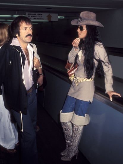 Los looks de Cher eran espectaculares tanto sobre el escenario, en su propio programa, donde su diseñador de referencia era Bob Mackey, como en su vida cotidiana. Aquí, con un look hibrido entre vaquero e indio acompañada de su marido al que estaba a punto de dejar. (Photo by Ron Galella, Ltd./Ron Galella Collection via Getty Images)