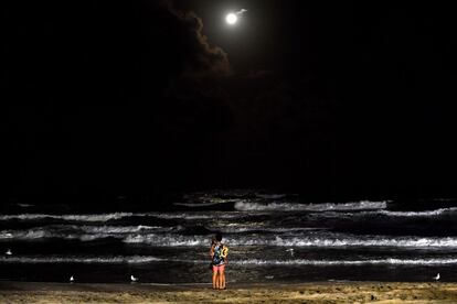 Um casal se beija em uma praia sob a lua cheia em Gold Coast (Austrália), no dia 31 de março de 2018