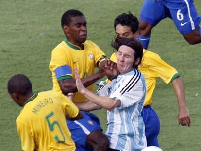 El central brasileño Juan comete falta a Messi, defendido también por Mineiro y Josué.