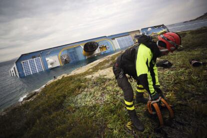 Un trabajador de los equipos de rescate se prepara frente al crucero hundido, junto al puerto de la isla de Giglio.