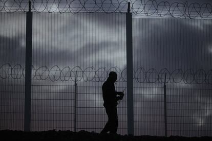 Un inmigrante camina tras la valla que le impide cruzar al campamento de inmigrantes de Calais (Francia).
