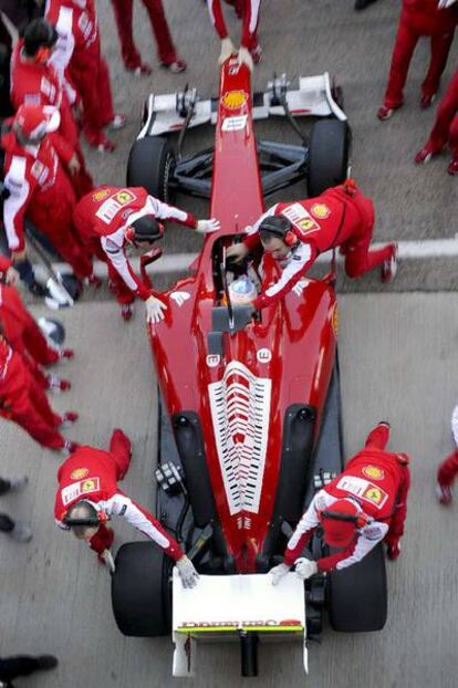 Los operarios ayudan a introducir el coche de Alonso en el taller al término de la sesión.