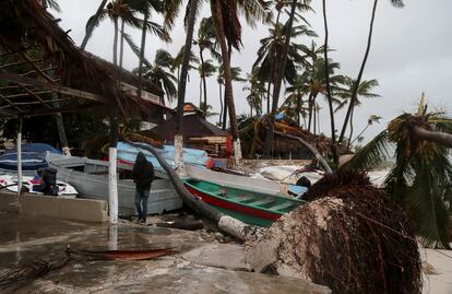 Un hombre camina entre palmeras caídas y cabañas destruídas tras el paso de 'Fiona' en una playa de Punta Cana.