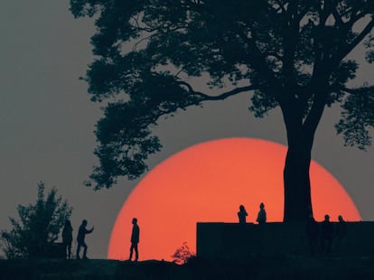 Un grupo de personas se reúne para ver la última puesta de sol del año 2077 del calendario nepalí en la colina del árbol único en Katmandú (Nepal).