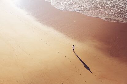 Un hombre andando por una playa del Algarve, Portugal.