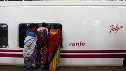 Varias personas observan un tren Talgo a su llegada a Bombay. 