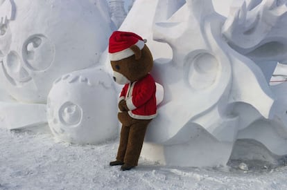 Un animador infantil, convertido en oso, descansa sobre una de las esculturas en la ciudad del hielo, el 5 de enero de 2015.