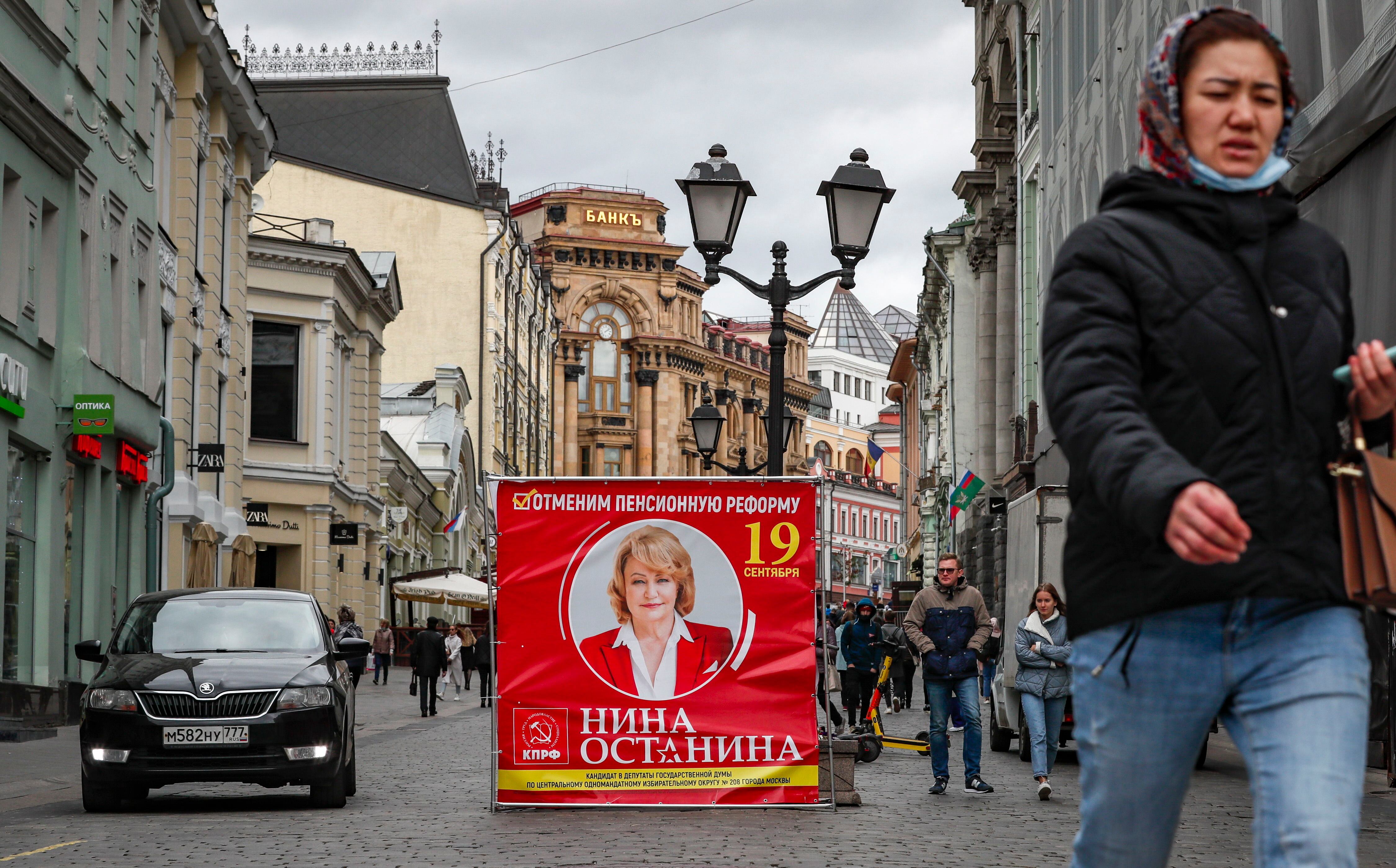 Varias personas caminan junto a un cartel de campaña del Partido Comunista, en una calle de Moscú, este miércoles. 