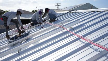 Trabajadores instalan el cableado para una instalación solar en el techo de una empresa en Barbados.