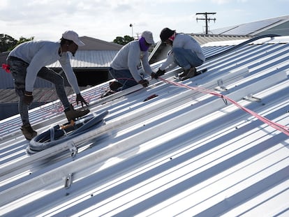Trabajadores instalan el cableado para una instalación solar en el techo de una empresa en Barbados.