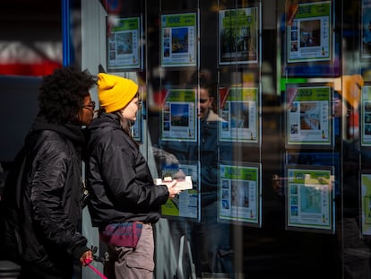 Dos jóvenes miran los precios de la vivienda en una agencia inmobiliaria en Madrid.
