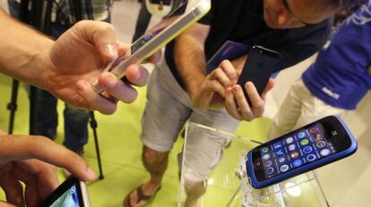 Varias personas observan un smartphone una tienda de telefon&iacute;a de Madrid