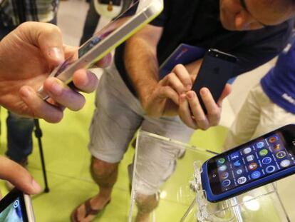 Varias personas observan un smartphone una tienda de telefon&iacute;a de Madrid