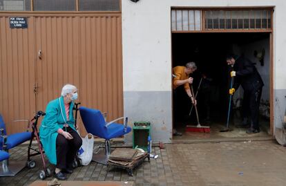 Una mujer observa a dos voluntarios achicando agua de su casa tras las inundaciones registradas en Villava, Navarra, este sábado.