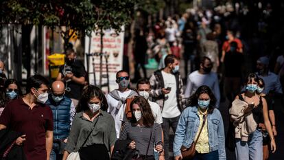 Decenas de personas caminan por la calle de la Montera en Madrid el primer día del confinamiento perimetral tras aprobar el estado de alarma.