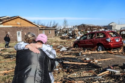 Duas pessoas se abraçam do lado de fora de um abrigo para mulheres e crianças destruído por um tornado em Mayfield. O presidente Joe Biden chamou os tornados que atingiram as regiões sul e central dos Estados Unidos de uma "tragédia inimaginável". "Talvez o mais devastador de nossa história."