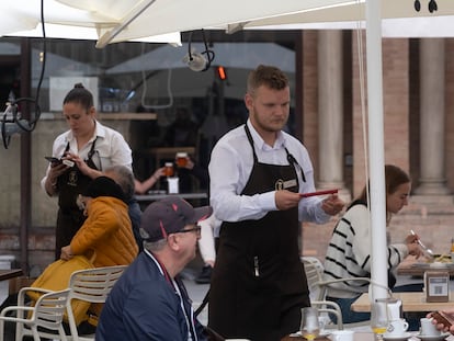 Un camarero atiende a varios clientes en una terraza de un bar de Sevilla.