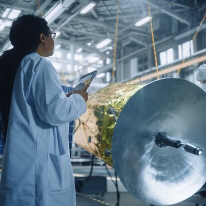 Female Engineer Uses Digital Tablet Computer while Working on Satellite Construction. Aerospace Agency: Scientist Overseeing Building, Assembly and Manufacturing of Spacecraft for Space Mission