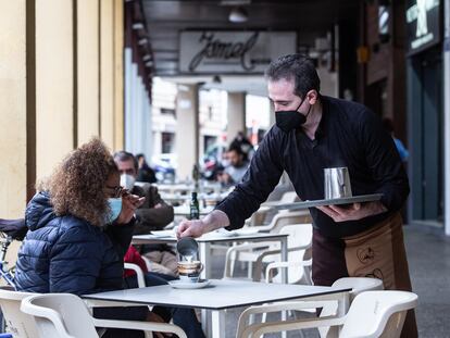 Un camarero sirve un café a una clienta en Badajoz, Extremadura (España).