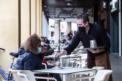 Un camarero sirve un café a una clienta en la Cafetería Tristana, durante el primer día de apertura de bares y restaurantes en Badajoz, Extremadura.