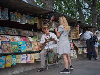 Alain Papillaud (74 años) atiende a una turista en su puesto de 'bouquiniste'.