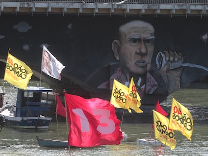 Barcos com bandeiras de políticos na bacia do Pina, ao lado de favela de palafitas.