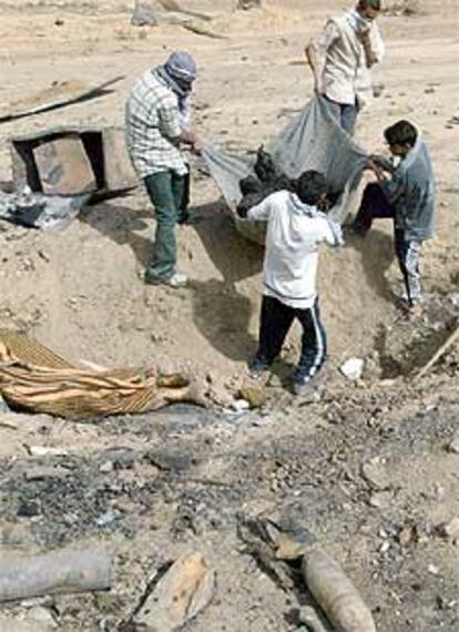 Cuatro voluntarios iraquíes trasladan un cadáver en una autopista cercana a Bagdad.